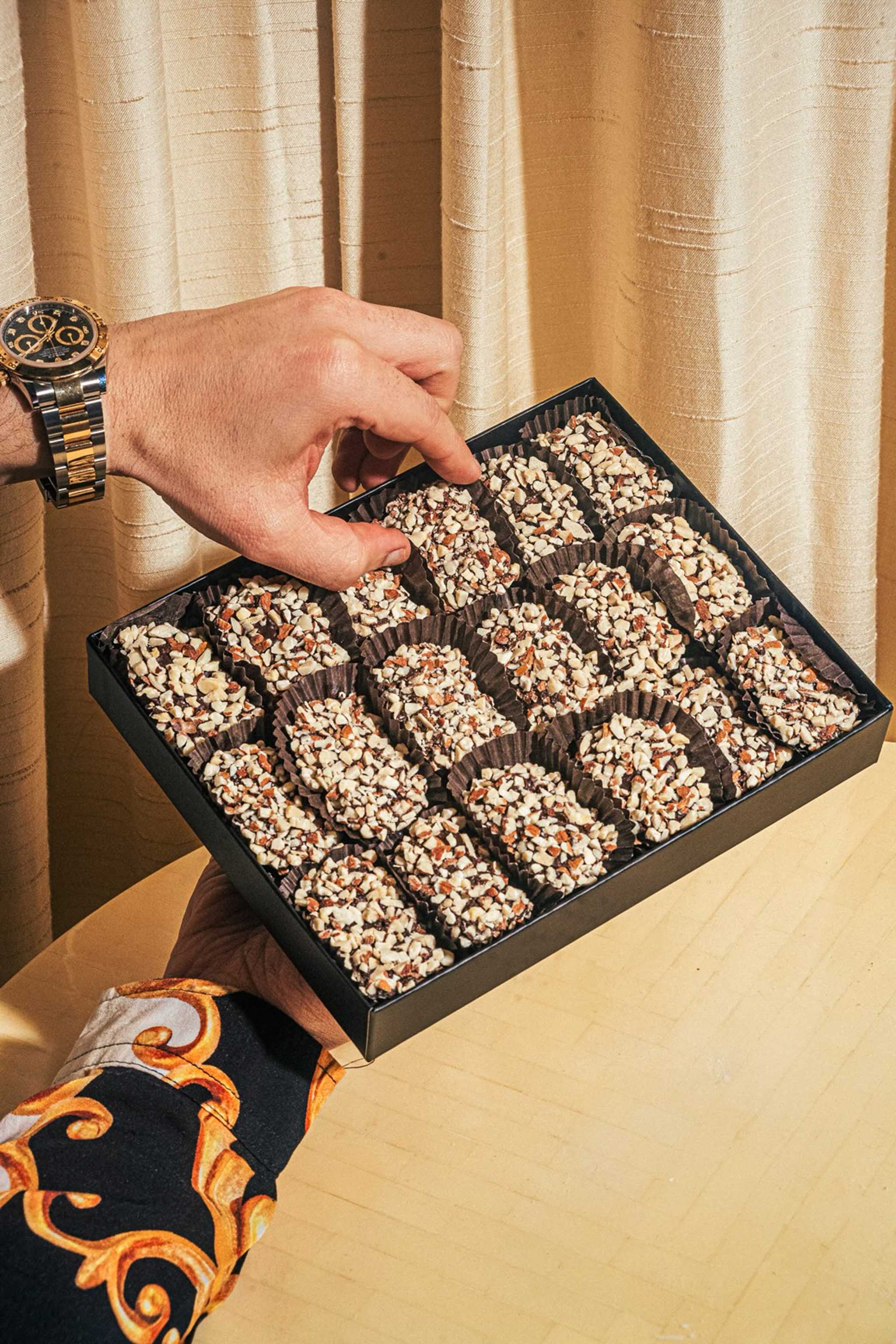 A hand selecting a nut-covered Compartes chocolate